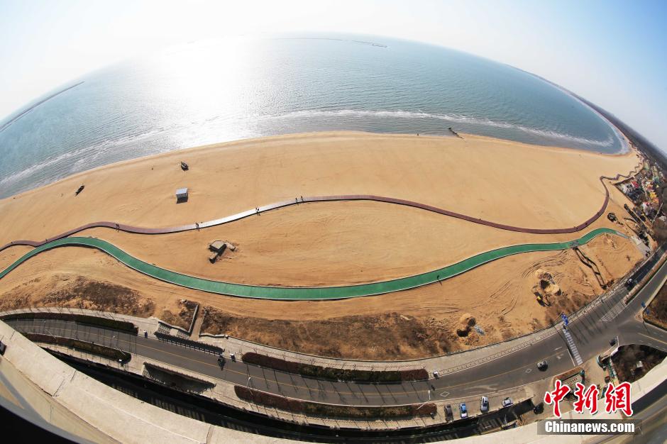 3月13日，秦皇島萬米臨海沙灘木棧道。據(jù)了解，該木棧道全長(zhǎng)約4200米，與北戴河區(qū)原有的7500米木棧道對(duì)接后全線總長(zhǎng)度1.17萬米，整個(gè)木棧道東起秦皇島體育基地游船碼頭，西至北戴河濕地公園，呈波浪形蜿蜒10.4公里海岸線。 中新社發(fā) 曹建雄 攝 CNSPHOTO